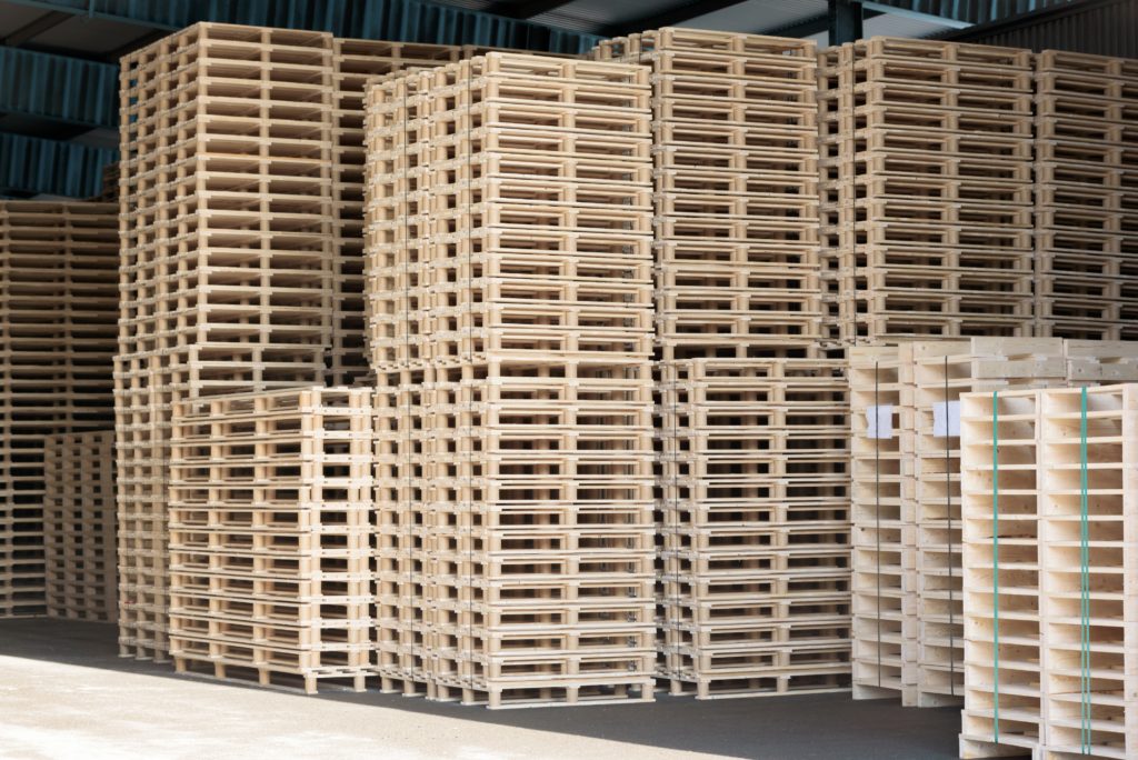 Lots of pallets stacked and ready for use. These are newly manufactured ones in open storage building.